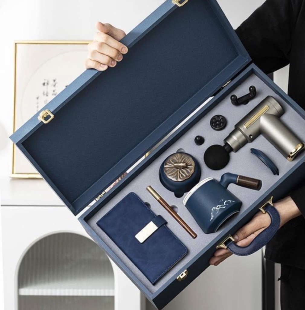 Blue gift case with massage gun, mug, tea jar, notebook, and pen